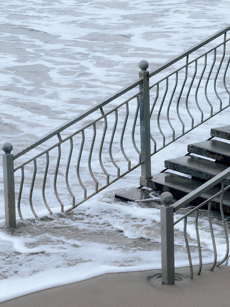 Metal staircase leading into the ocean waves, creating a surreal beach scene.